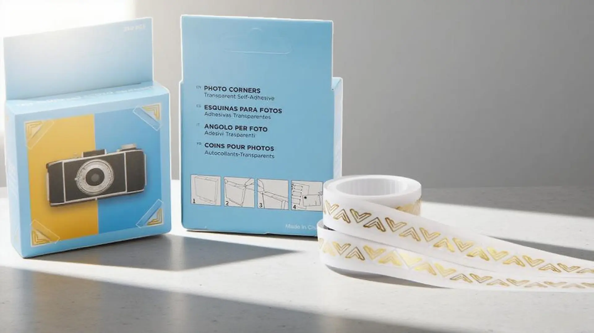 Une image professionnelle des boîtes de produits de coins photo de SENDA et d'un rouleau de coins photo dorés sur un bureau de studio moderne.